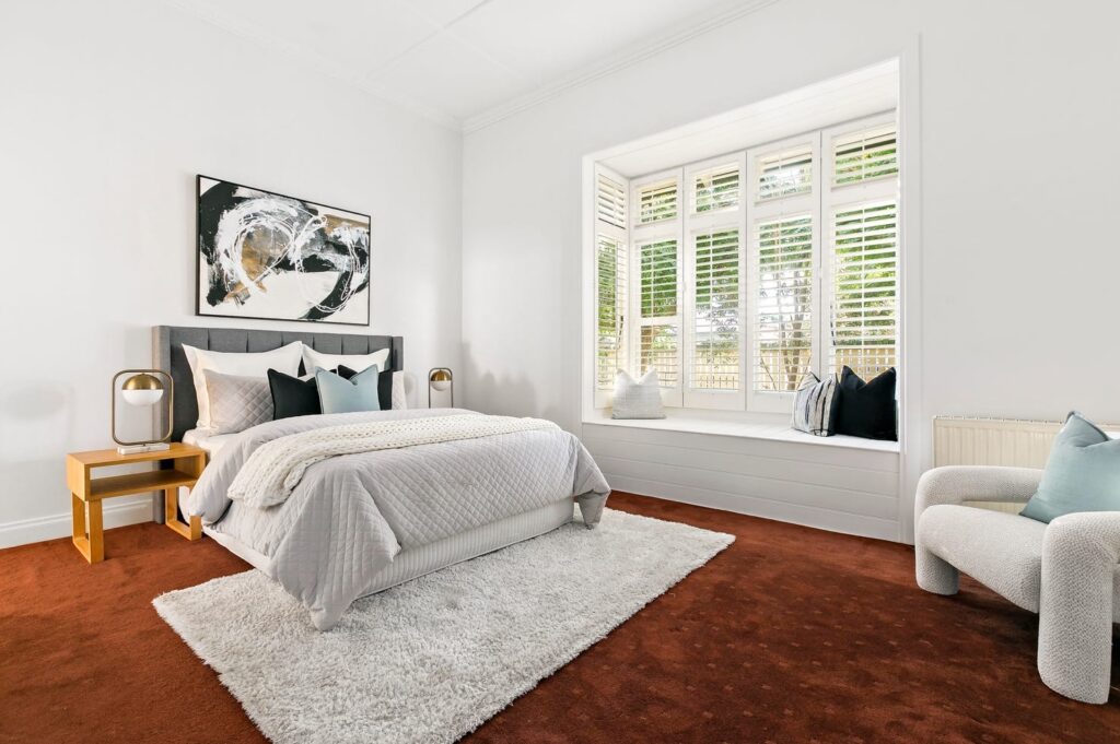 red royal carpet main bedroom stage. Coburg house with natural lighting and modern black, white and gold art with matching cushions.