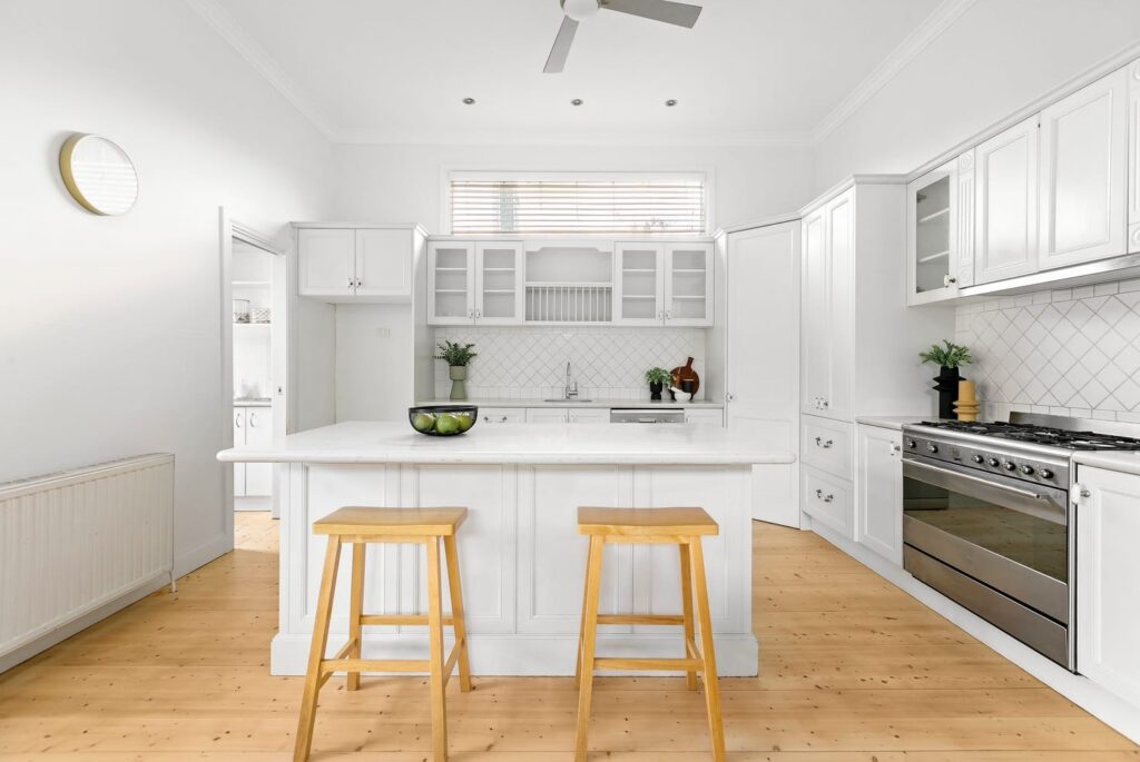 white staged Coburg island bench. 2 timber stools, very bright white.