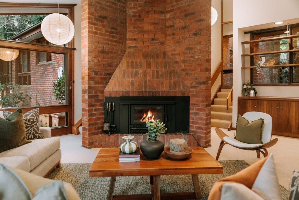 Living room with a statement brick fireplace and warm timber accents in a house in Olinda