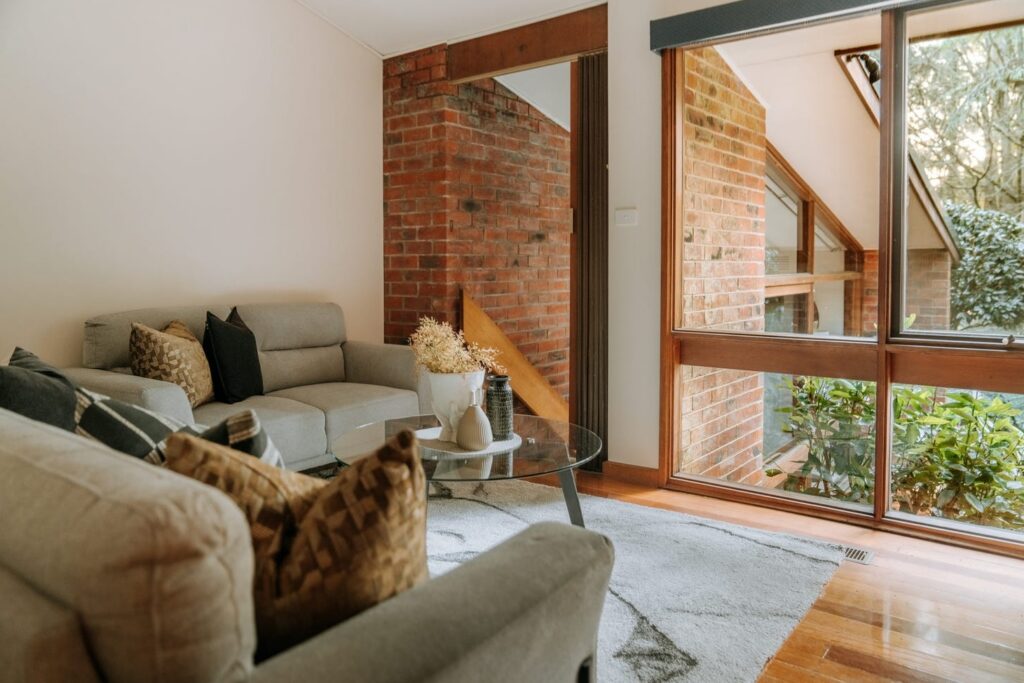 Cosy sitting room with neutral furniture, exposed brick and large windows in a house in Olinda