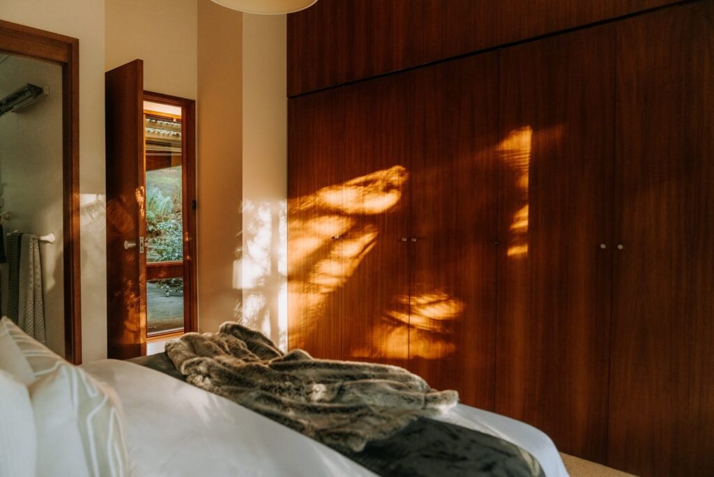 Timber built-in wardrobes illuminated by natural sunlight in a bedroom in a house in Olinda