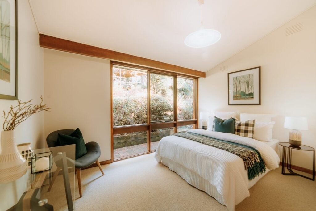 Staged bedroom with white bedding, deep green accents and garden views in a house in Olinda
