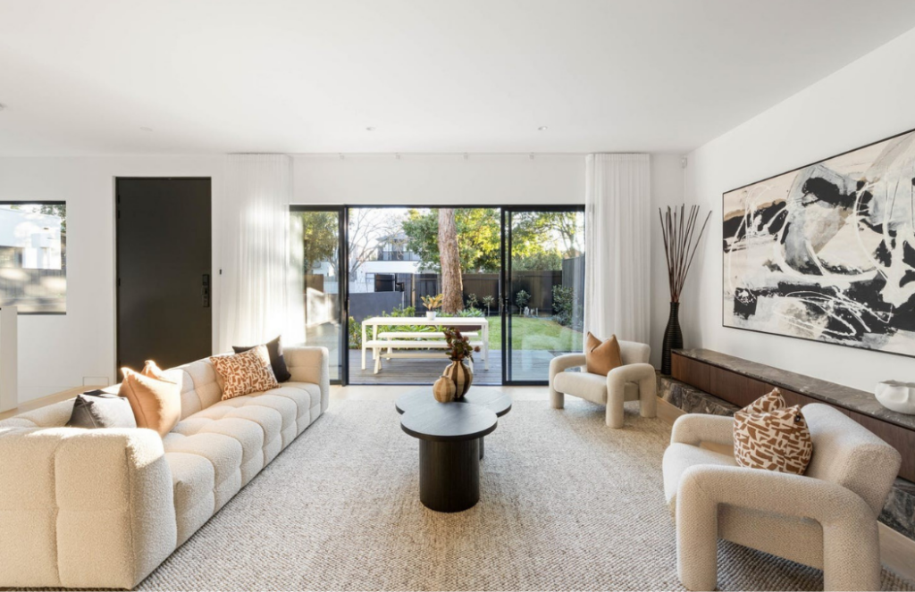 Modern Glen iris living room stage. High ceilings, modern white couches paired with matching arm chairs. Big modern black frame windows.