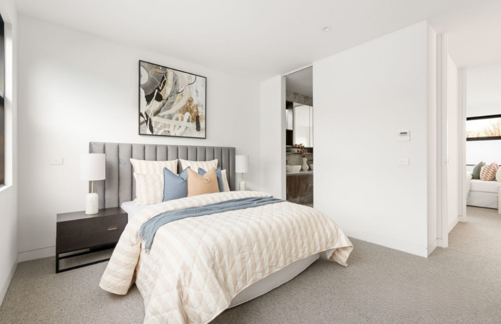 Soft blues mixed with warm whites in a staged bedroom in Glen Iris. light grey headboard and a matched artwork, with light grey carpet and white walls.