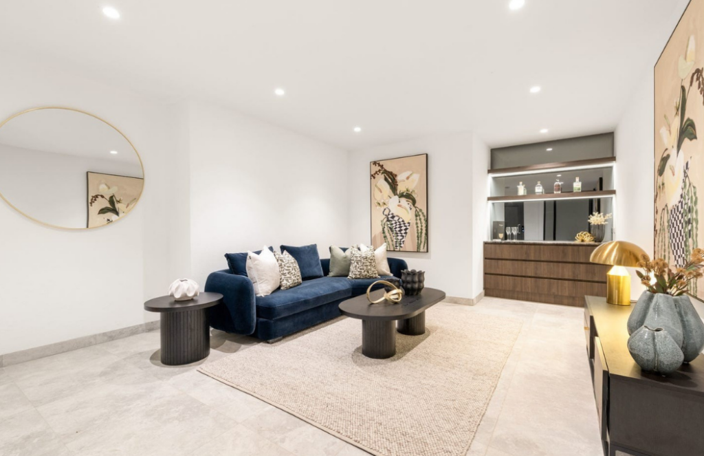 Downstairs staged rumpus room at Glen Iris. Bright walls and flooring staged with a dark royal blue couch.