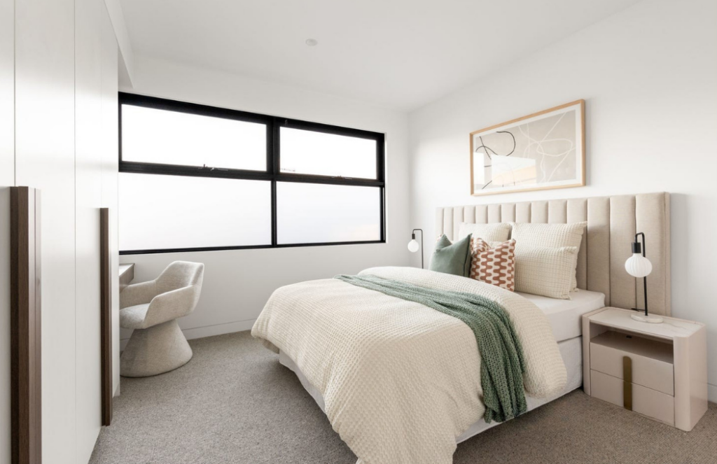 queen modern bedroom in Glen iris stage. Large windows, light brown pallet with touches of green.
