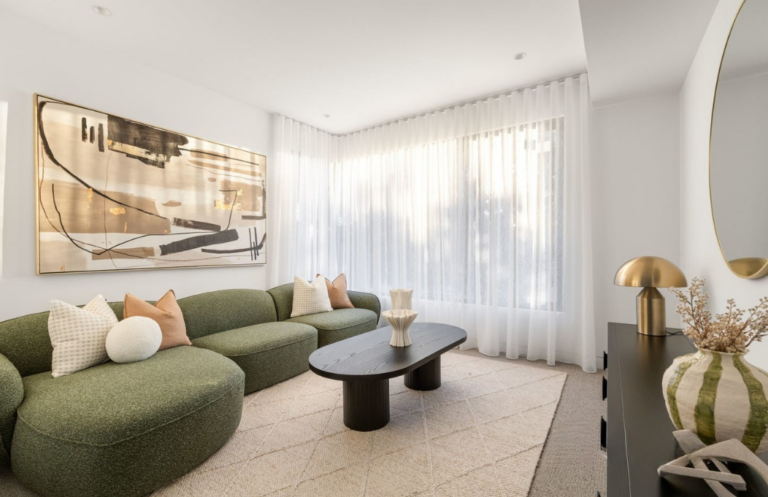 Olive green stage couch in living room at Glen Iris. Warm brushed colour pallet with light browns and creams. black curved coffee table.