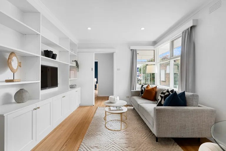 a staged unit lounge room, with on couch and modern white walls.