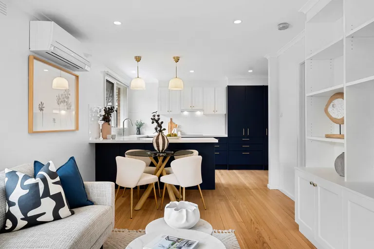 A stunning staged lounge room in Murrumbeena, showing a lounge room and small dinning, with a navy and white styled modern kitchen.