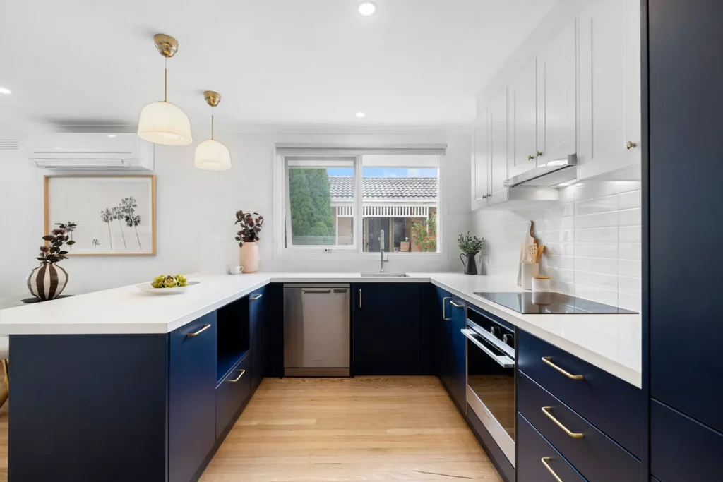 a modern staged navy kitchen with open windows and bright colours.
