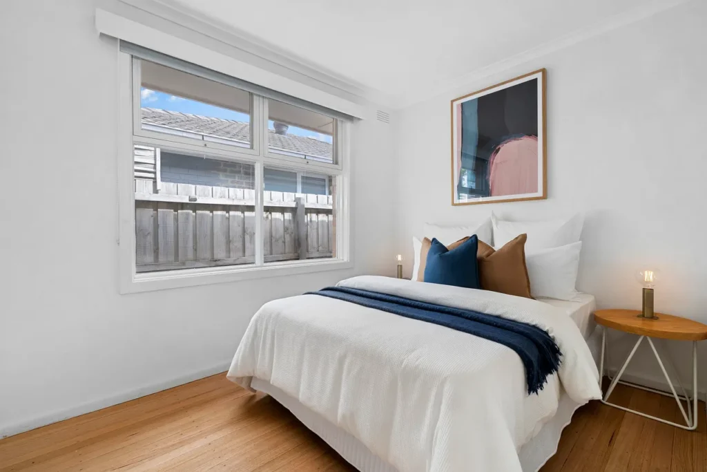 a modern staged secondary bedroom with bright white walls and navy cushions to match the kitchen.