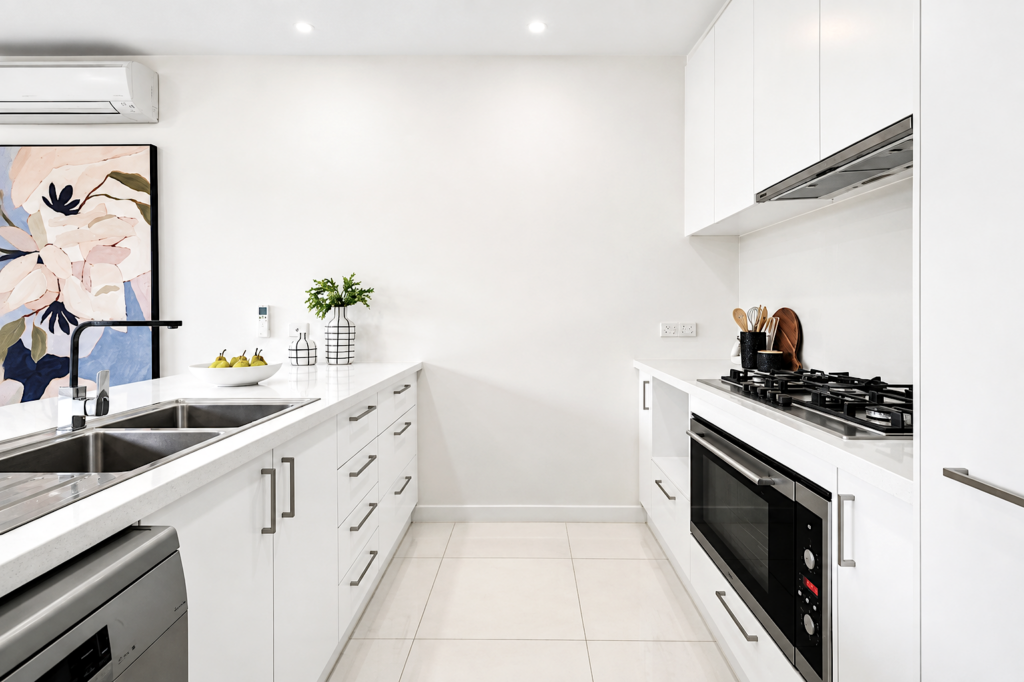 Modern white galley kitchen with stone benchtops, gas cooktop and quality appliances in a townhouse in Carnegie.