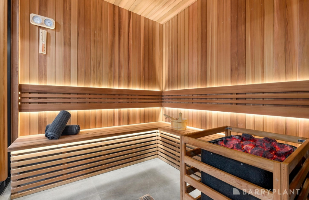 Timber-lined home sauna with illuminated bench seating and sauna heater in a luxury house in Doncaster.