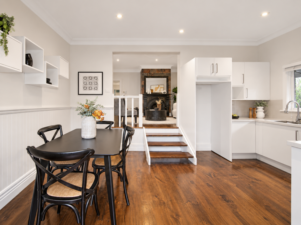 Open-plan kitchen and dining area professionally staged with black dining furniture and timber floors
