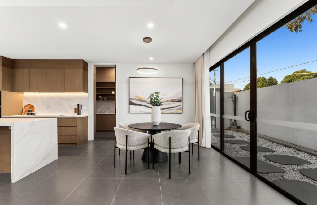 Modern dining area with black round table, upholstered chairs and floor-to-ceiling glazing in a luxury house in Doncaster.