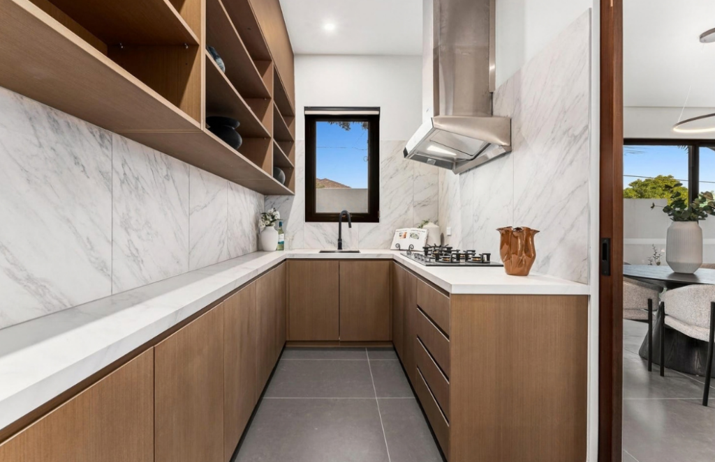 Timber and marble galley kitchen with open shelving and stainless steel rangehood in a luxury house in Doncaster.