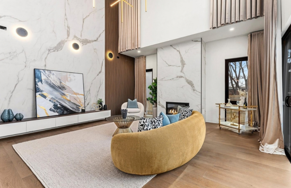 Double-height living room with mustard curved sofa, abstract artwork and marble fireplace in a luxury house in Doncaster.