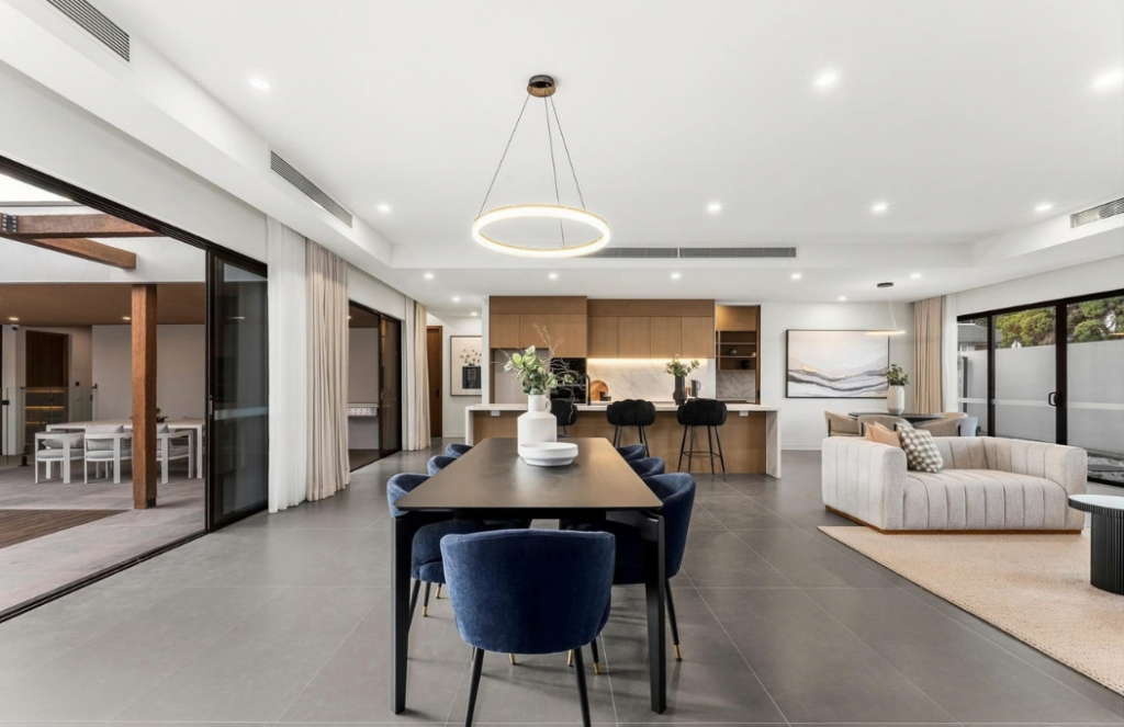 Open-plan dining area with navy chairs, black dining table and contemporary kitchen beyond in a luxury house in Doncaster.