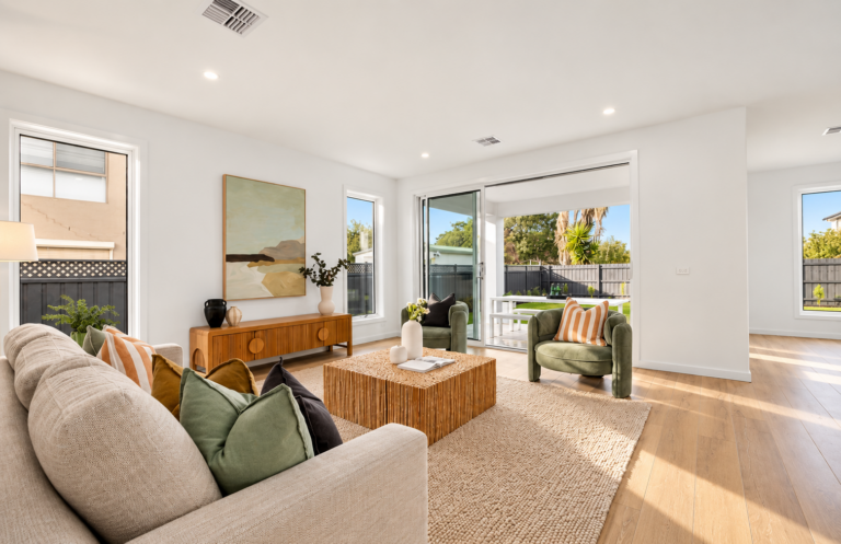 A staged beach house in Dromana with a timber entertainment unit and green arm chairs.
