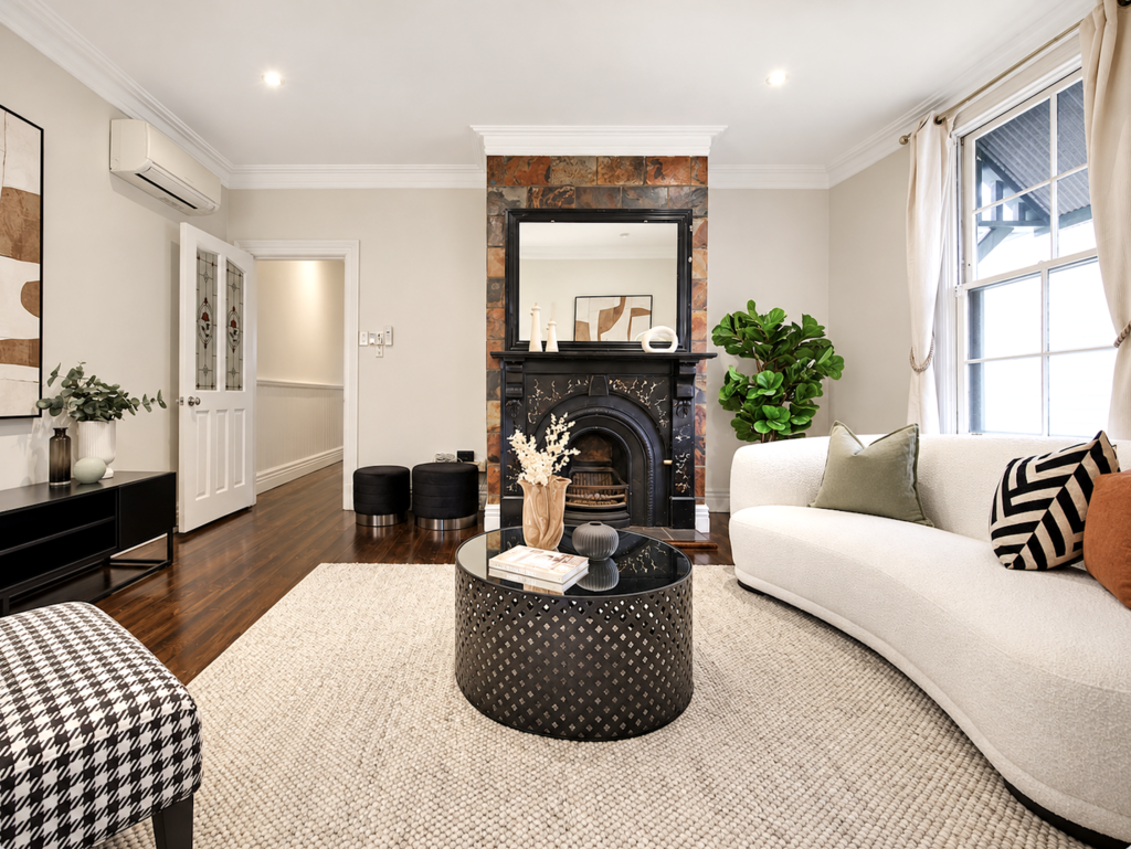 Professionally staged Melbourne living room with curved white sofa, black accents and period fireplace