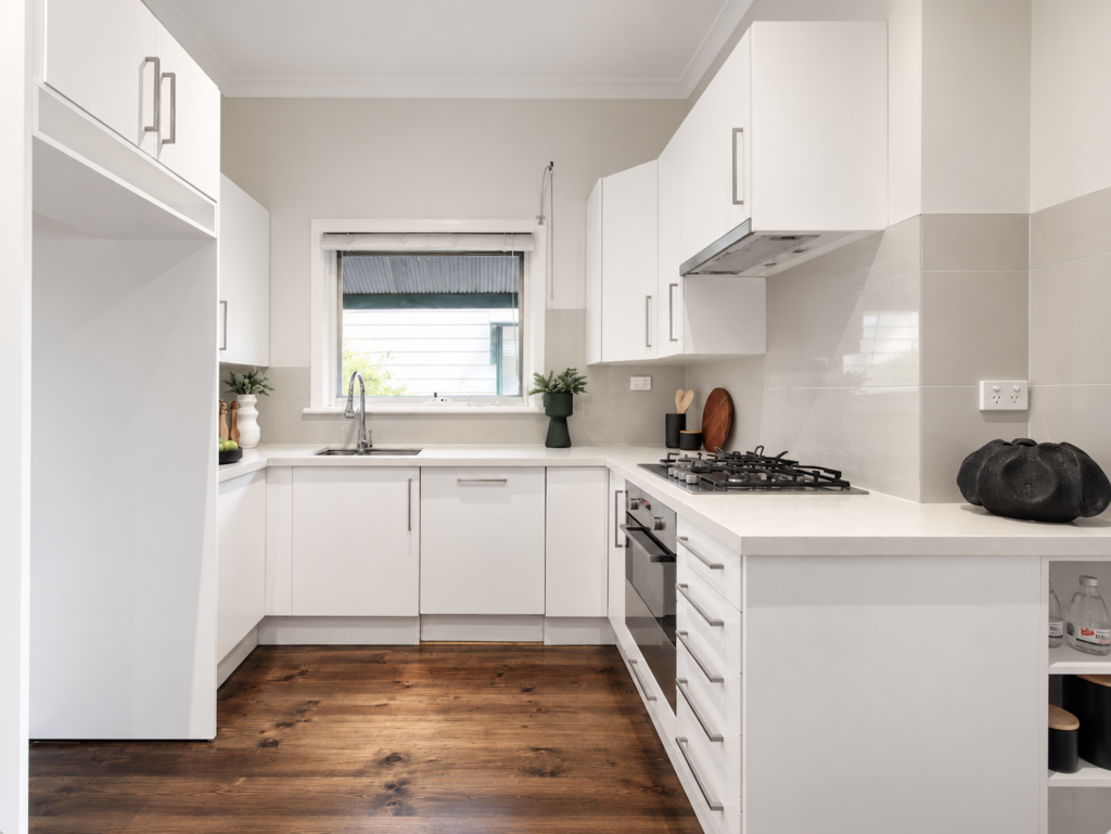 Bright white kitchen styled with minimal accessories and warm timber flooring in Melbourne property