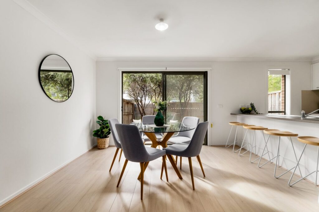 Staged dining area with glass table beside a modern kitchen in a townhouse in Croydon