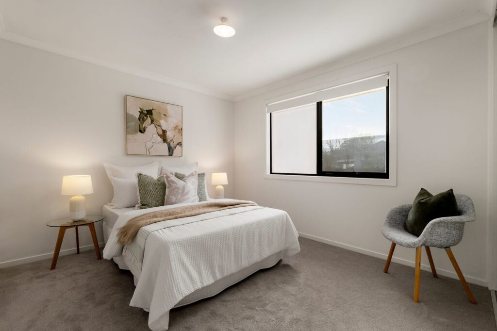 Staged bedroom with neutral bedding, green accents and modern artwork in a townhouse in Croydon