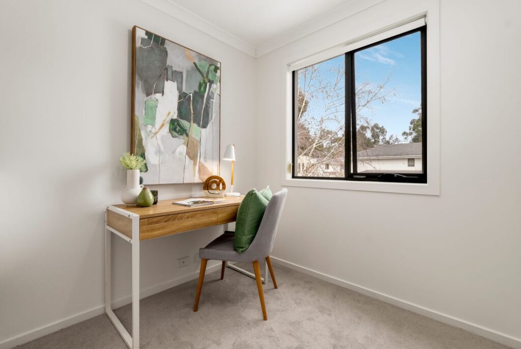 Staged home office with timber desk, green accents and abstract artwork in a townhouse in Croydon