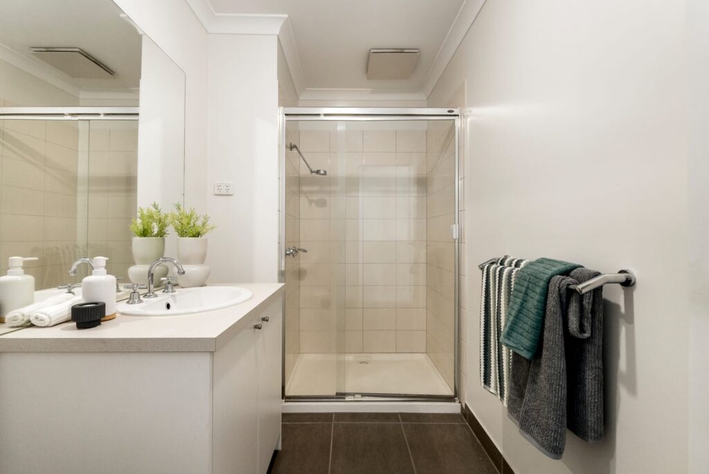 Modern bathroom styled with green towels and simple accessories in a townhouse in Croydon