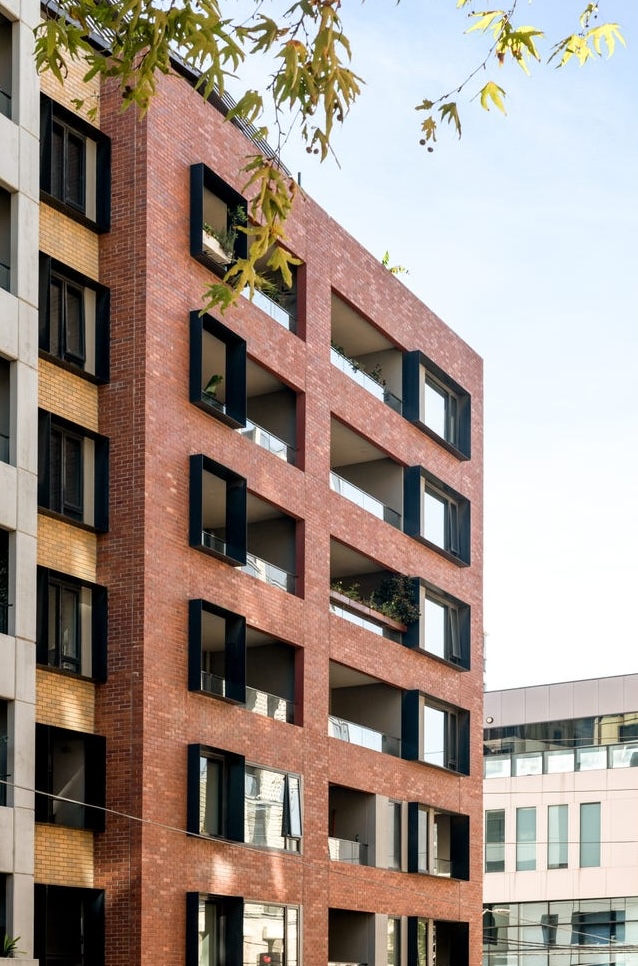 Modern red brick apartment building exterior with black-framed windows and balconies in Collingwood.