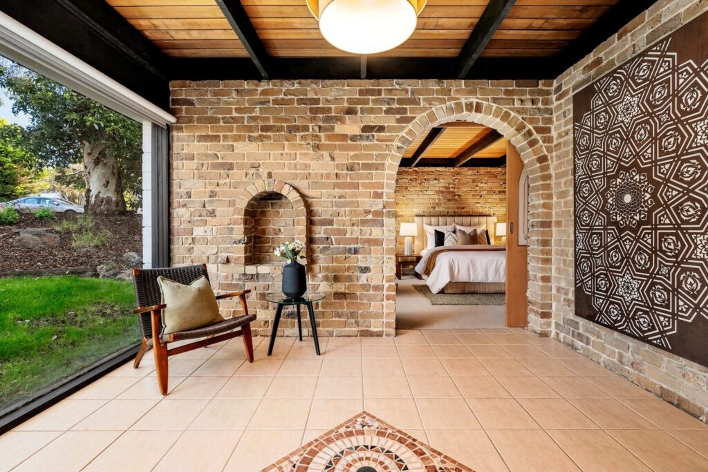 Staged sitting area with exposed brick walls, timber ceiling, arched doorway and statement wall art in a brick house in Vermont.
